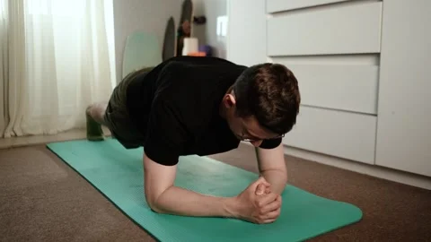 A young, athletic man exercises at home. Stretching, push-ups Видео 335139637