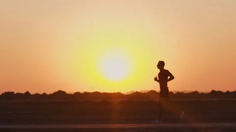 Young athletic man jogging on beach dirt road at sunset Video stock 132069752