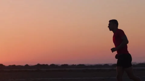 Young athletic man jogging at beach at sunset Stock Footage 132069891