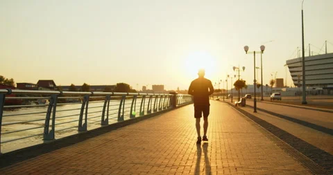 Young athletic man jogging on city street in golden sunset light Stock Footage 276544650