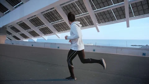 Young athletic man jogging outdoor at modern city area in evening sunlight near Stock Footage 105754270