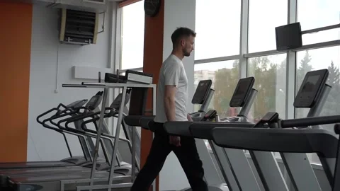Young athletic man jogging on treadmill in sport gym before training Stock Footage 132172616