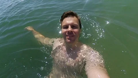 Young athletic man making selfie in the sea and swims on the back Video stock 80316907