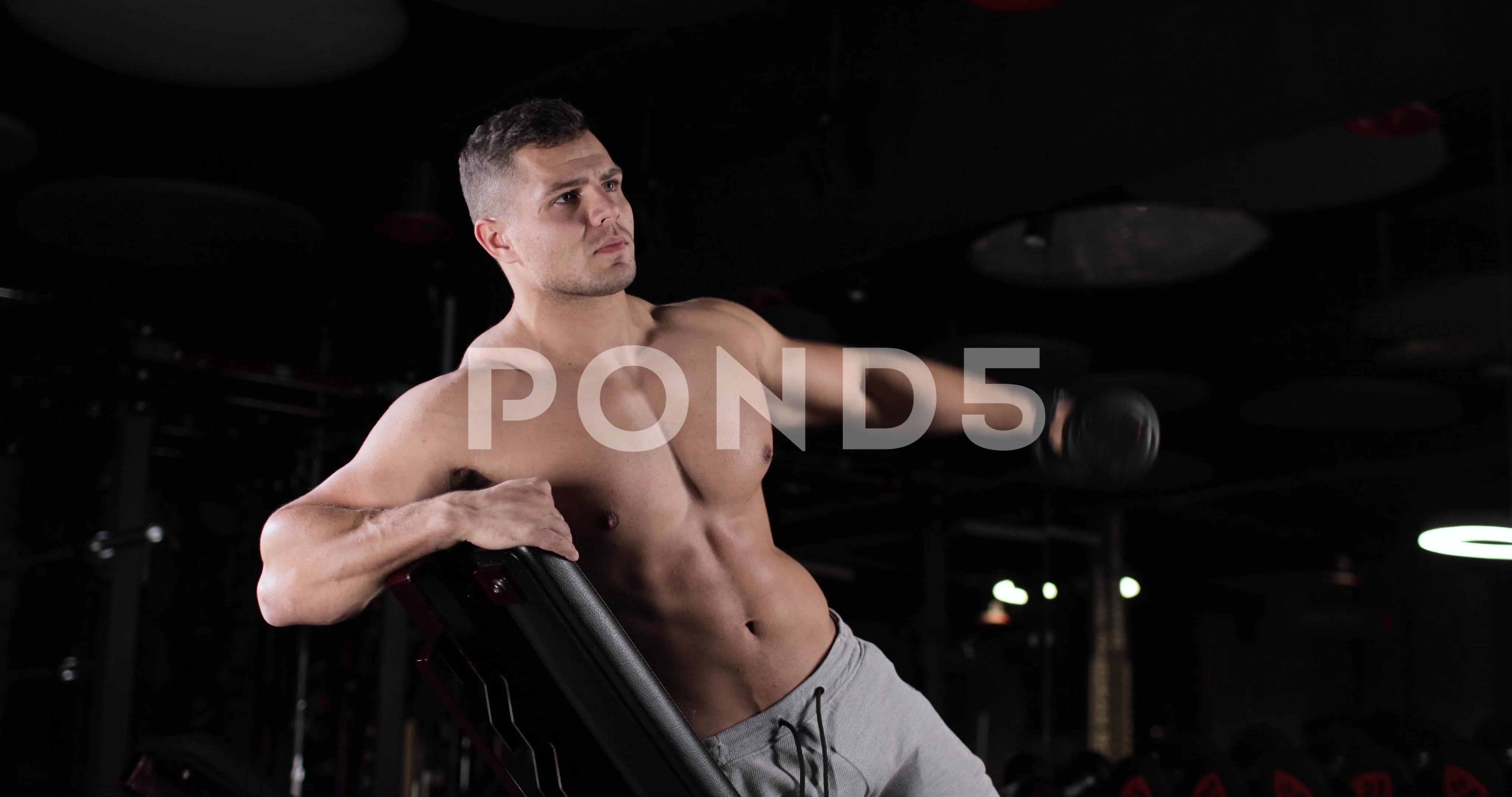 Young athletic man with a naked torso doing exercises with dumbbells  leaning on