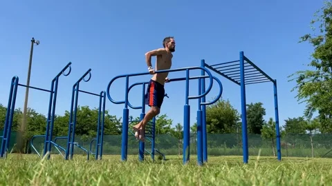Young athletic man pulls himself up on the horizontal bar of the sports ground Stock Footage 248531048