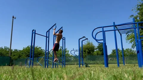 Young athletic man pulls himself up on the horizontal bar of the sports ground Stock Footage 248531107