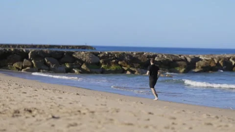 Young athletic man running barefoot on the beach Stock Footage 320462737