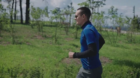 A young athletic man runs through a landscaped and green park. Sports lifestyle Stock-Footage 243514944