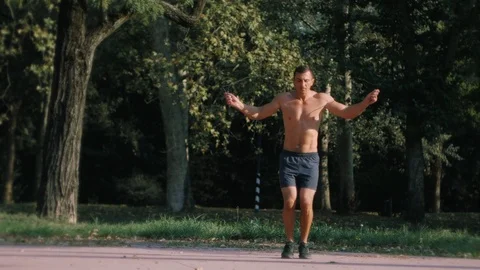 Young athletic man skipping with a jump rope outdoors in the park in slow motion Stock Footage 100019950