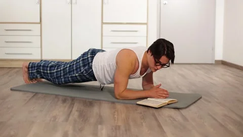Young athletic man is standing in elbow plank, workouting in morning living room Vidéo 259489681