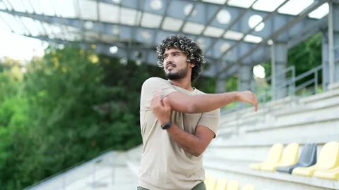 Young athletic man stretching and warm up in outdoor stadium, preparing for work Stock Footage 283812799