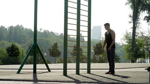 Young, athletic man stretching his legs on the sports ground during the morning Stock Footage 79816869