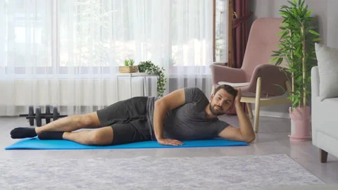Young athletic man training at home stretching stretching legs. Video stock 219727604