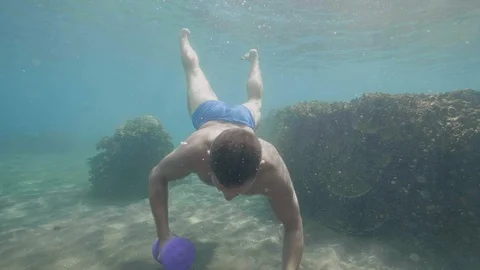 Young athletic man underwater is making set of exercises with dumbbells. Video stock 107139575