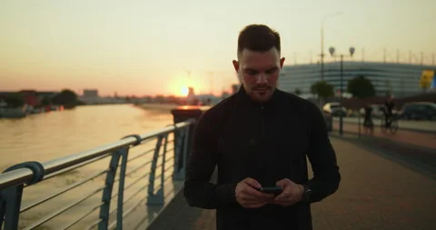 Young athletic man using smartphone after workout in the city at sunset Stock Footage 276546185