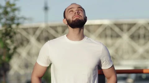 Young athletic man in white t-shirt doing warm up exercises outdoors Stock Footage 143496306
