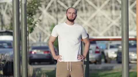 Young athletic man in white t-shirt rotating his head to warm up outdoors Video stock 143496708