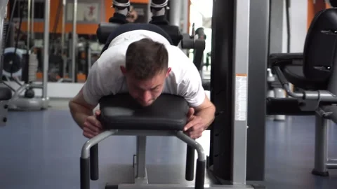 Young athletic man working out on a leg curl machine and toning his legs Stock Footage 132172326