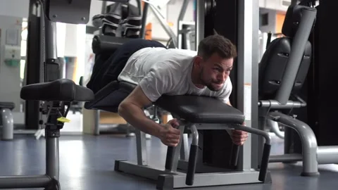 Young athletic man working out on a leg curl machine and toning his legs. Side Stock Footage 132173143