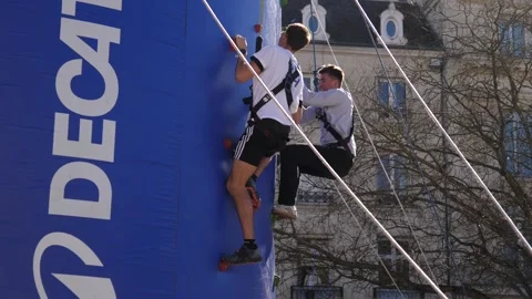 Young athletic men climb an inflatable wall with holds, attached to a harness Vidéo 331062214