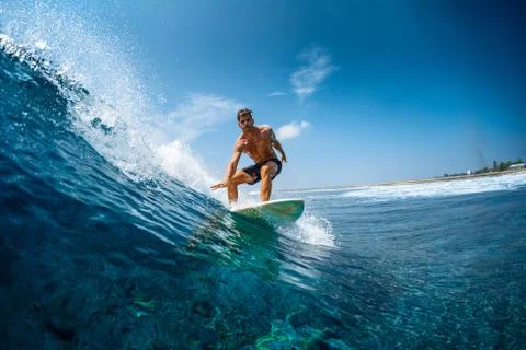 Young athletic surfer rides the wave in tropics with splashes. Jailbreaks sur Stock Photos