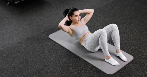 A young athletic woman does an exercise on the abdominal press, lies on the Stock Footage 167847515