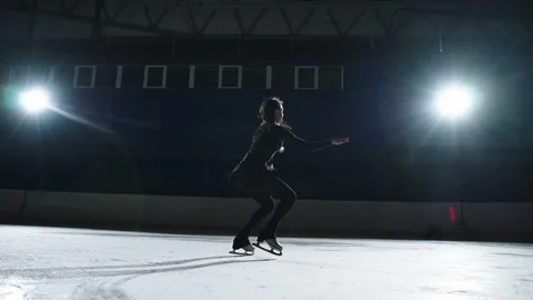 Young athletic woman is performing elements of figure skating on ice rink Stock Footage 150881393