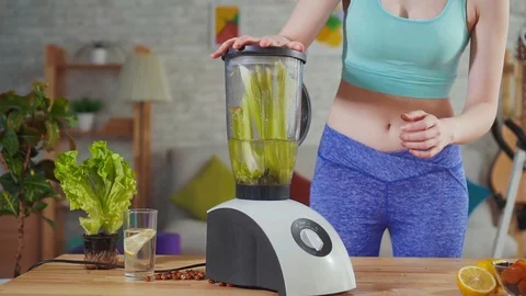 Young athletic woman throws celery in the mixer slow mo Stock Footage 113451245