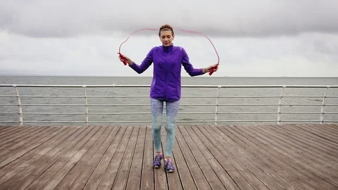 Young athtletic woman working out on the jump rope. Slim girl jumping on a Stock Footage