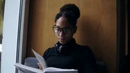 The Young Attractive Afro-American Woman Is Reading The Book On The Wide Window Stock Footage