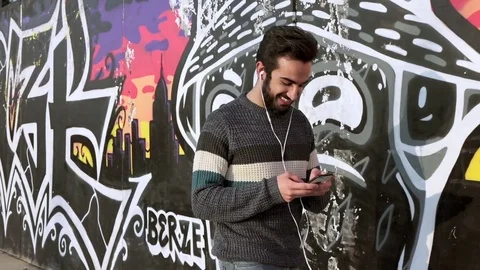 Young attractive and smiling man walking on the street chatting with cellphone Stock Footage 74700271