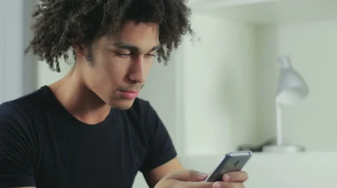 The young, attractive, black guy smiles broadly printing SMS to the friends Stock Footage 58587206