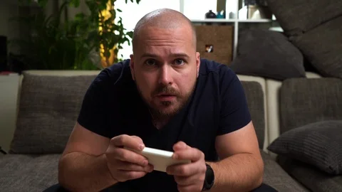 Young attractive bold and bearded guy sitting on the couch and playing console.. Stock Footage 112722674