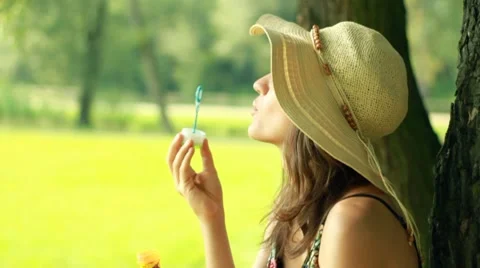 Young attractive brunette blowing bubbles in the park, slow motion Stock Footage 8583632