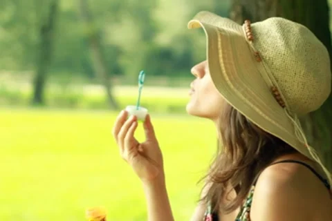 Young attractive brunette blowing bubbles in the park, slow motion Stock Footage 8583764