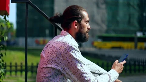 Young attractive brunette man using smartphone outside. Casual style. Business Stockbeeldmateriaal 131006555