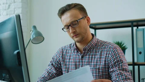 Young attractive business man in the glasses reading report but feeling annoying Stock Footage
