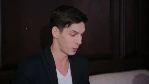 Young attractive charismatic guy sitting on the couch actively gesturing during Stock Footage 75634518