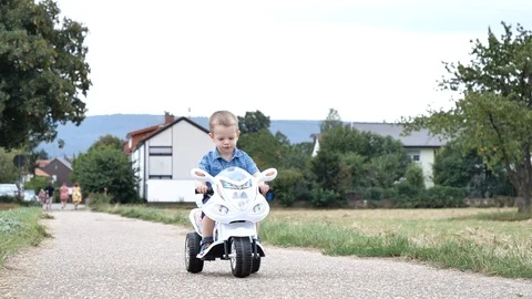 Young Attractive Child Boy Driving With Electric Toy Scooter on Outdoor Stock Footage 114013147