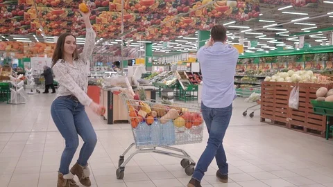 Young attractive couple dancing and laughing in supermarket through fresh Stock Footage 125101923
