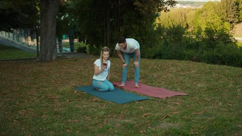 Young attractive couple doing exercises on mats in the park having rest using Stock Footage 117568461