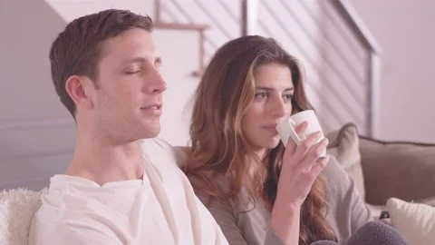 Young attractive couple drinking coffee, and relaxing in their living room, Stock Footage 83001280