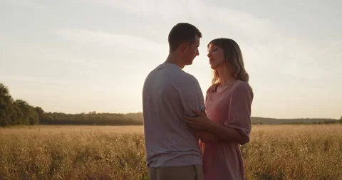 Young attractive couple having a date at sunset in a golden wheat field Stock Footage 237810570