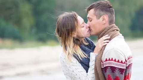 Young attractive couple in knitted sweaters on a cliff on sea shore Stock-Footage 70358853