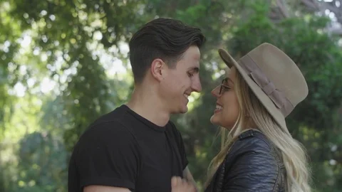 Young attractive couple lovingly embrace, and look at the camera at a park Stock Footage