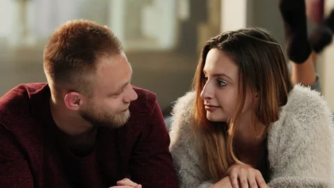 Young attractive couple lying on couch and having a talk Stock Footage