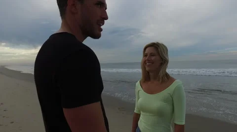 A young, attractive couple talking on the beach at sunrise. Santa Monica, Stock Footage 68050934