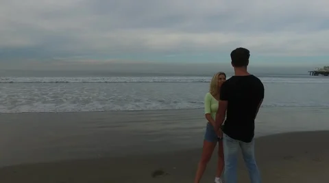A young, attractive couple talking on the beach at sunrise. Santa Monica, Stock Footage 68050964