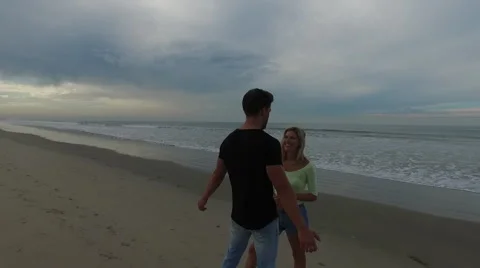 A young, attractive couple talking on the beach at sunrise. Santa Monica, Stock Footage 68050976