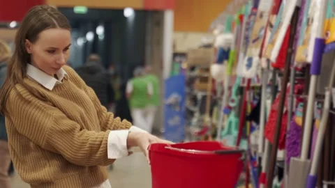 Young attractive customer choosing a plastic bucket in a home decor store Vídeos de archivo 173035709
